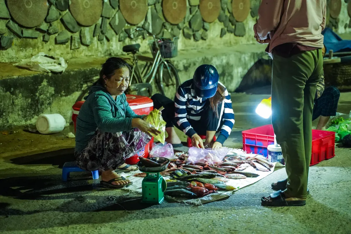 Two women selling fresh fish at a night market. Street vendor setup with fresh catch displayed.